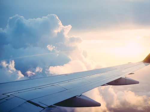 Aircraft wing above clouds, representing NRI investors
